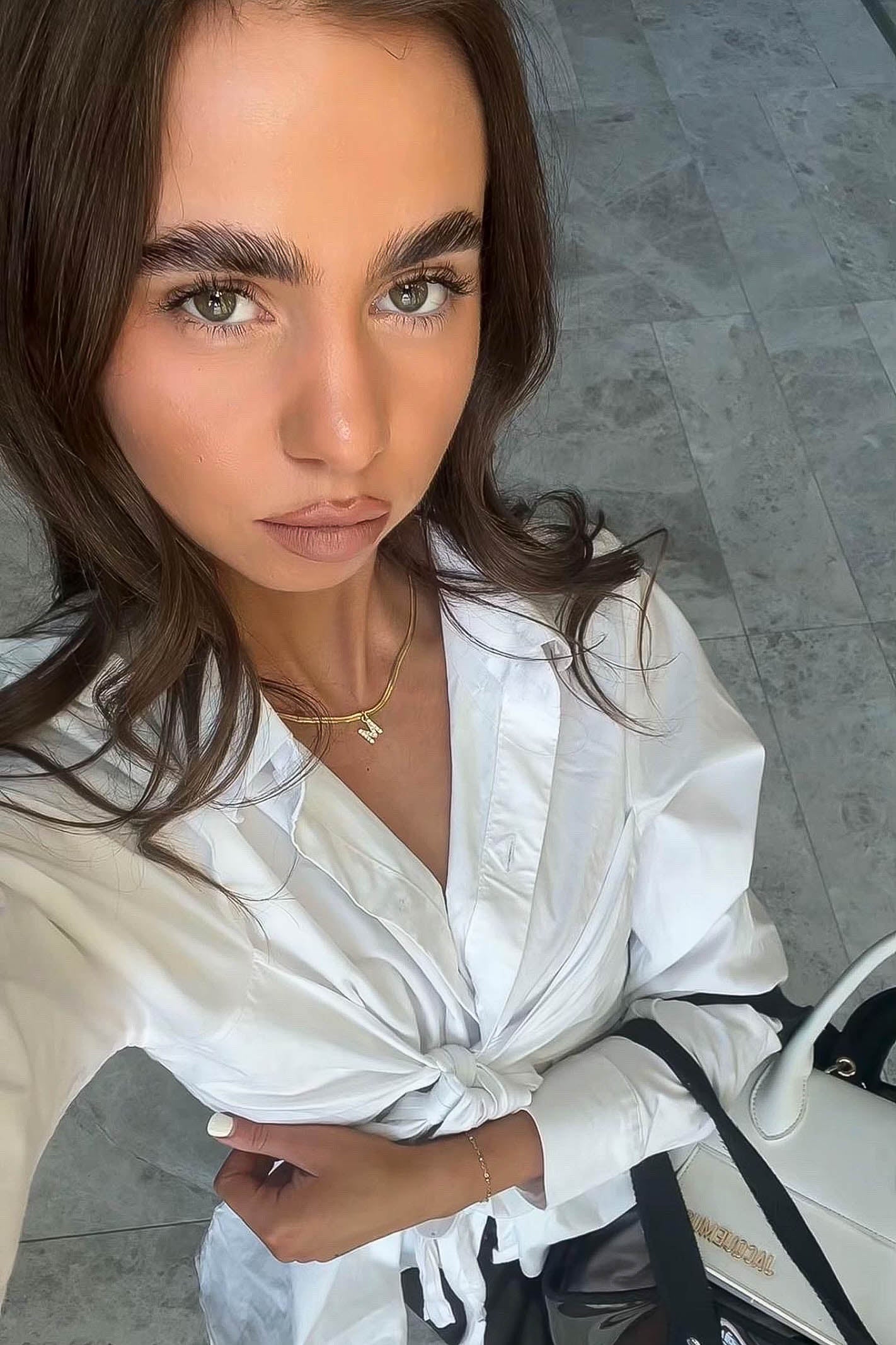 Woman wearing a white shirt with a gold letter necklace